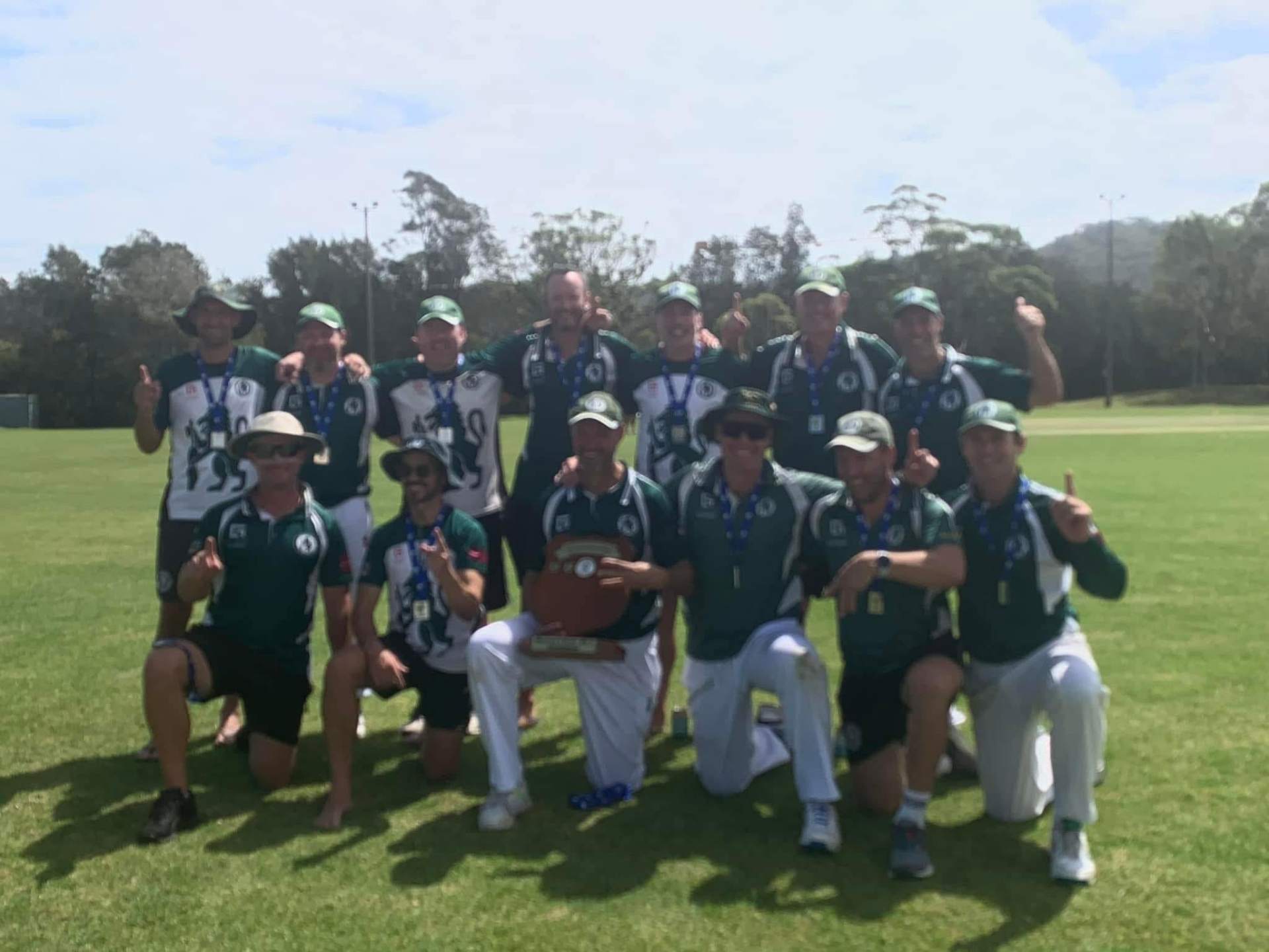 Men's premiership team on the field with medals and shield