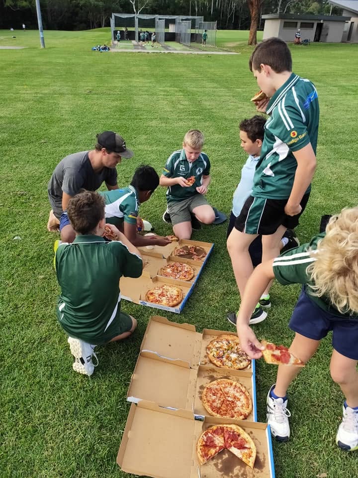 Coach and juniors digging into pizzas together